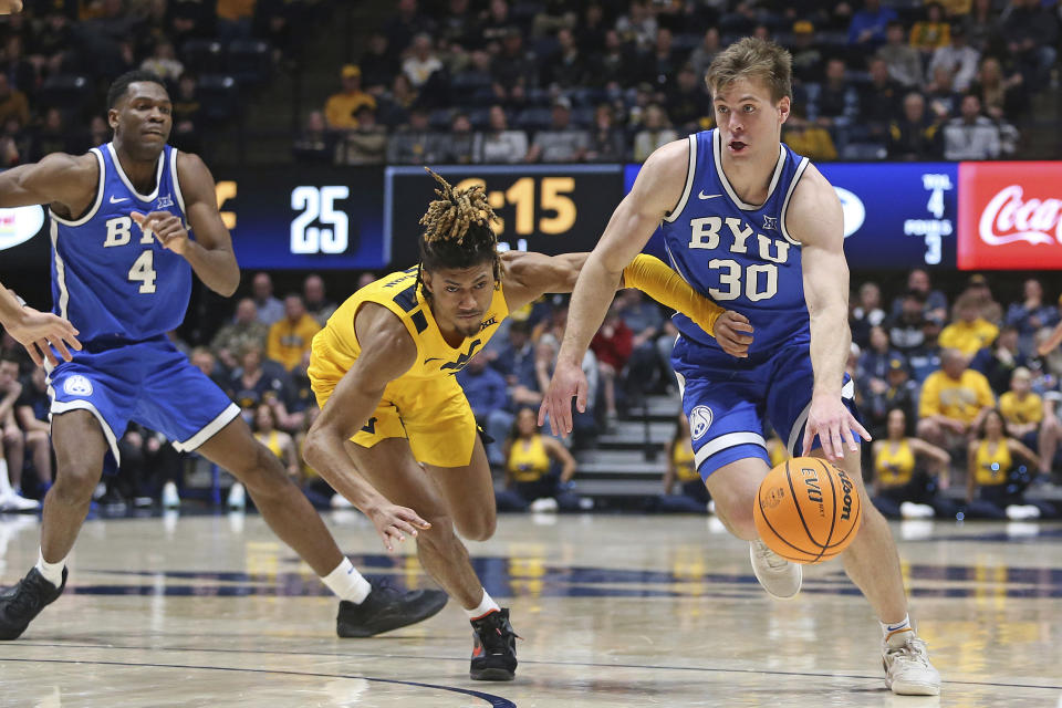 BYU guard Dallin Hall (30) is defended by West Virginia guard Noah Farrakhan, center, during the first half of an NCAA college basketball game Saturday, Feb. 3, 2024, in Morgantown, W.Va. (AP Photo/Kathleen Batten)