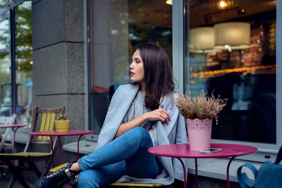 A woman sits waiting outside a cafe