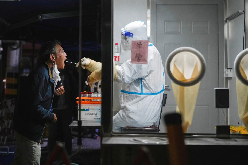 A medical worker in a protective suit collects a sample from a resident for nucleic acid testing, following the coronavirus disease (COVID-19) outbreak in Shanghai, China, on the day of the opening session of the 20th National Congress of the Communist Party of China, October 16, 2022. REUTERS/Aly Song