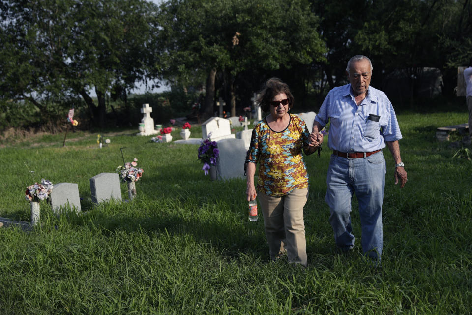 In this Wednesday, May 1, 2019, photo, Oliverio Yarrito, 80, and his wife, Odilia Yarrito, 79, walk among the gravestones at the Eli Jackson Cemetery in San Juan, Texas. Two graveyards are among several properties on the Mexican border that are under threat as the Trump administration rushes to build hundreds of miles of wall. The Eli Jackson Cemetery would likely be destroyed under current plans but family members are fighting the effort. (AP Photo/Eric Gay)