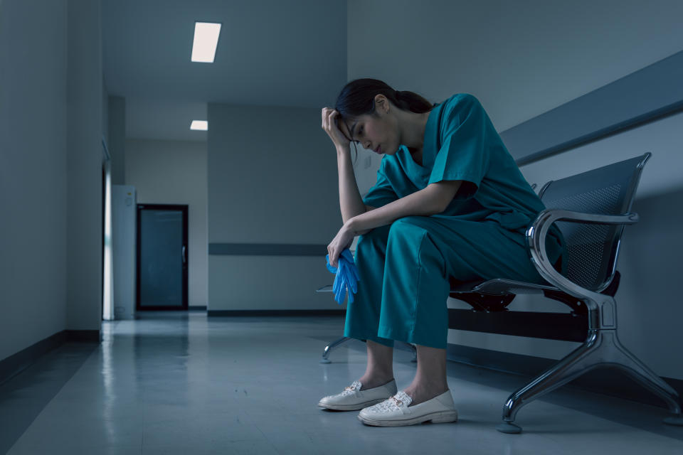 Medical nurse sitting down in a hospital corridor in frustration and grief 