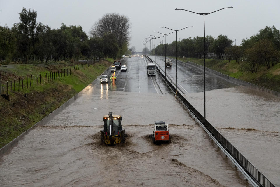 Workers in machinery tend to a flooded road in Santiago, Chile, Thursday, June 13, 2024. (AP Photo/Matias Basualdo)