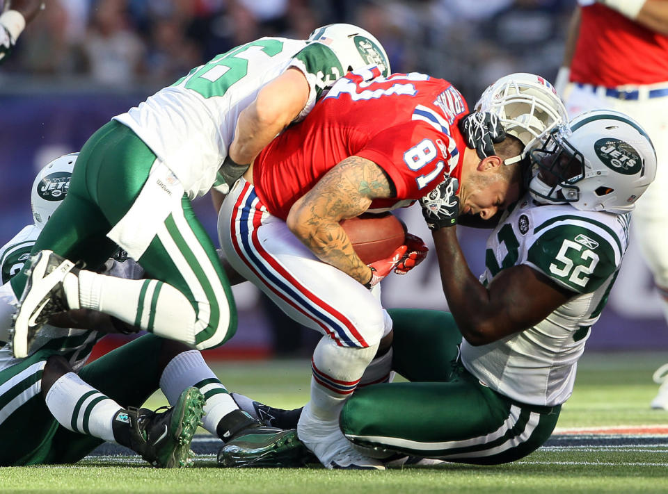 Aaron Hernandez #81 of the New England Patriots has his helmet ripped off by David Harris #52 of the New York Jets on October 9, 2011 at Gillette Stadium in Foxboro, Massachusetts. (Elsa/Getty Images)