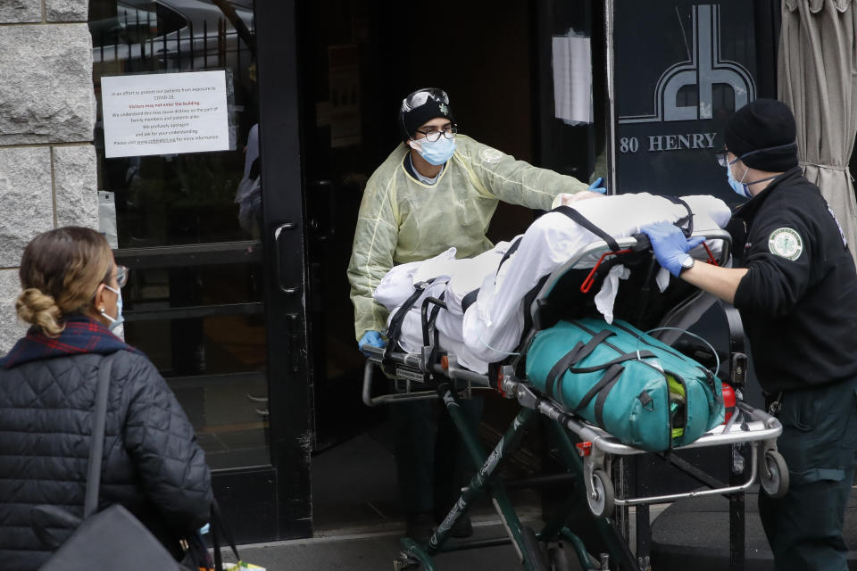 A patient is wheeled into Cobble Hill Health Center by emergency medical workers, Friday, April 17, 2020, in the Brooklyn borough of New York. The despair wrought on nursing homes by the coronavirus was laid bare Friday in a state survey identifying numerous New York facilities where multiple patients have died. (AP Photo/John Minchillo)