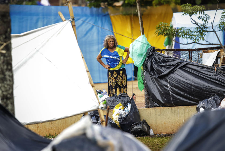 A woman watches police clear out an encampment set up by supporters of former Brazilian President Jair Bolsonaro outside army headquarters in Brasilia, Brazil, Monday, Jan. 9, 2023, the day after Bolsonaro supporters stormed government buildings in the capital. (AP Photo/Gustavo Moreno)