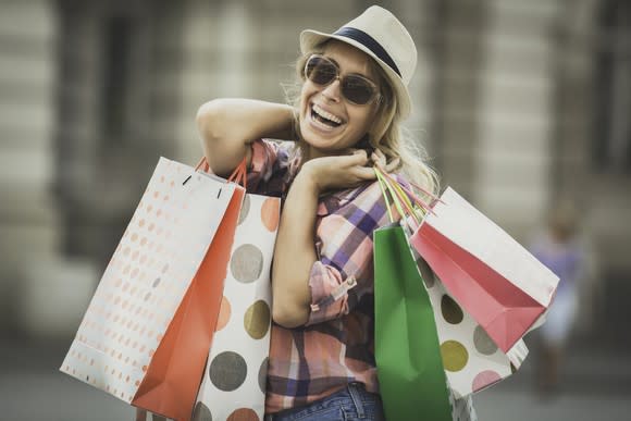 A smiling woman holds several shopping bags.