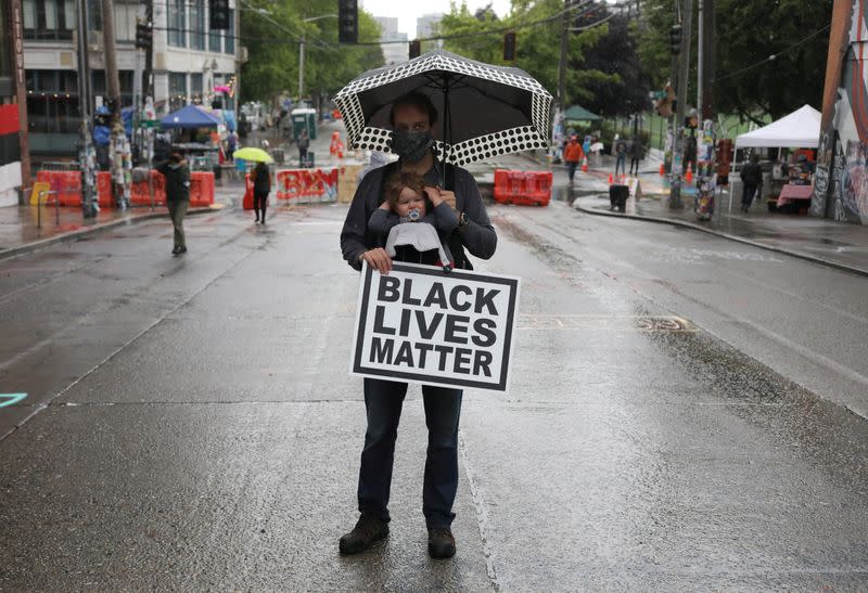 A man holds his child and a sign that reads 'Black Lives Matter', in Seattle