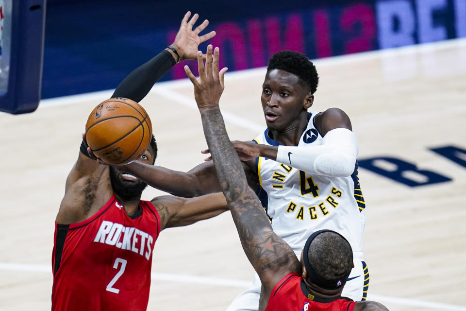 Indiana Pacers guard Victor Oladipo (4) shoots over Houston Rockets center DeMarcus Cousins (15) and guard David Nwaba (2) during the first quarter of an NBA basketball game in Indianapolis, Wednesday, Jan. 6, 2021. (AP Photo/Michael Conroy)