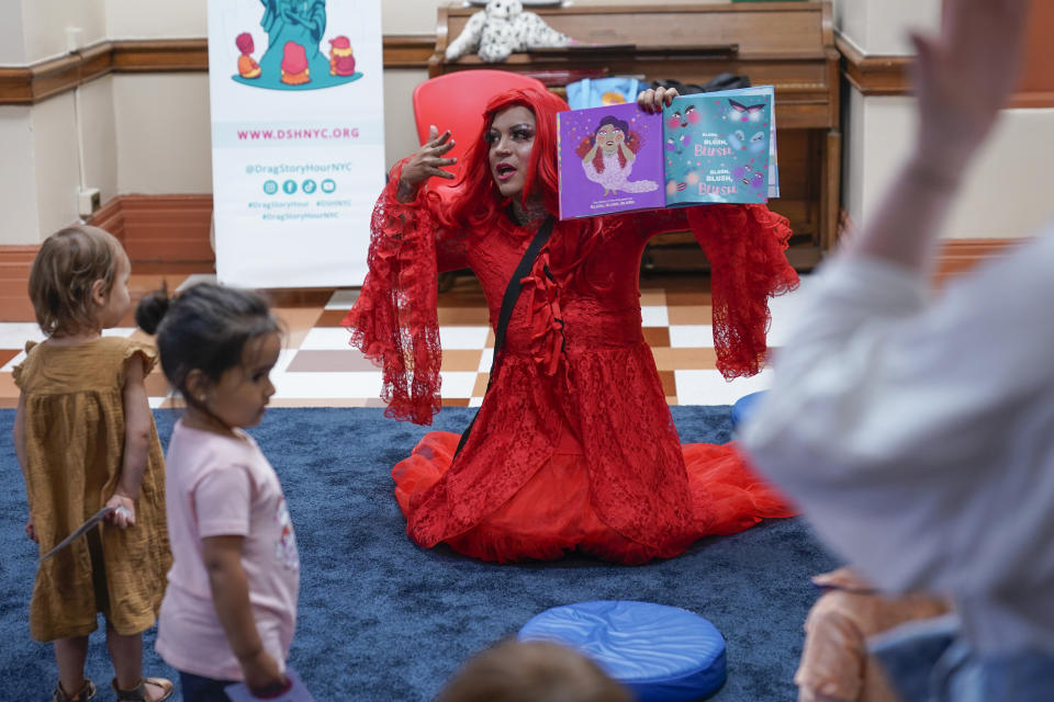 A drag queen who goes by the name Flame reads stories to children and their caretakers during a Drag Story Hour at a public library in New York, Friday, June 17, 2022. (AP Photo/Seth Wenig)