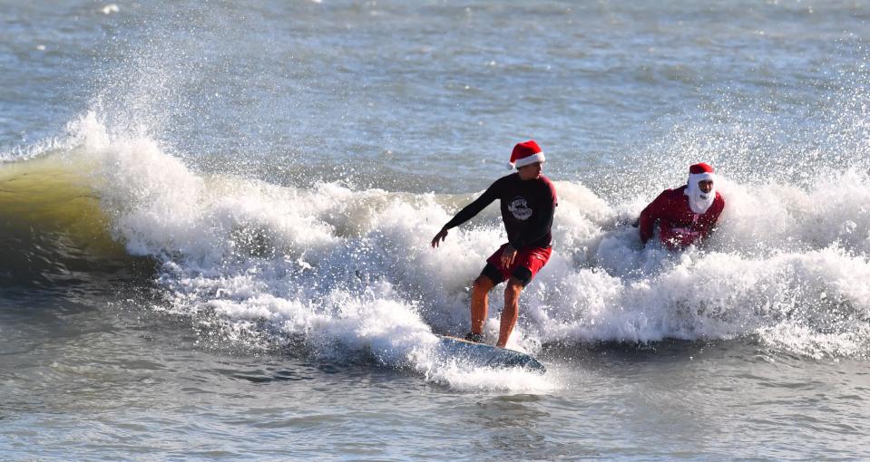 A pair of Surfing Santas share a wave on Christmas Eve morning in chilly Cocoa Beach.