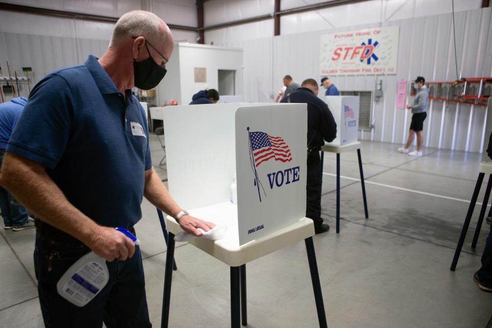 Poll worker Jerry Young, disinfects a voter booth at the Soldier Township Fire Department Station No. 72, Tuesday morning, Nov. 3, 2020, in Soldier Township, Kansas.