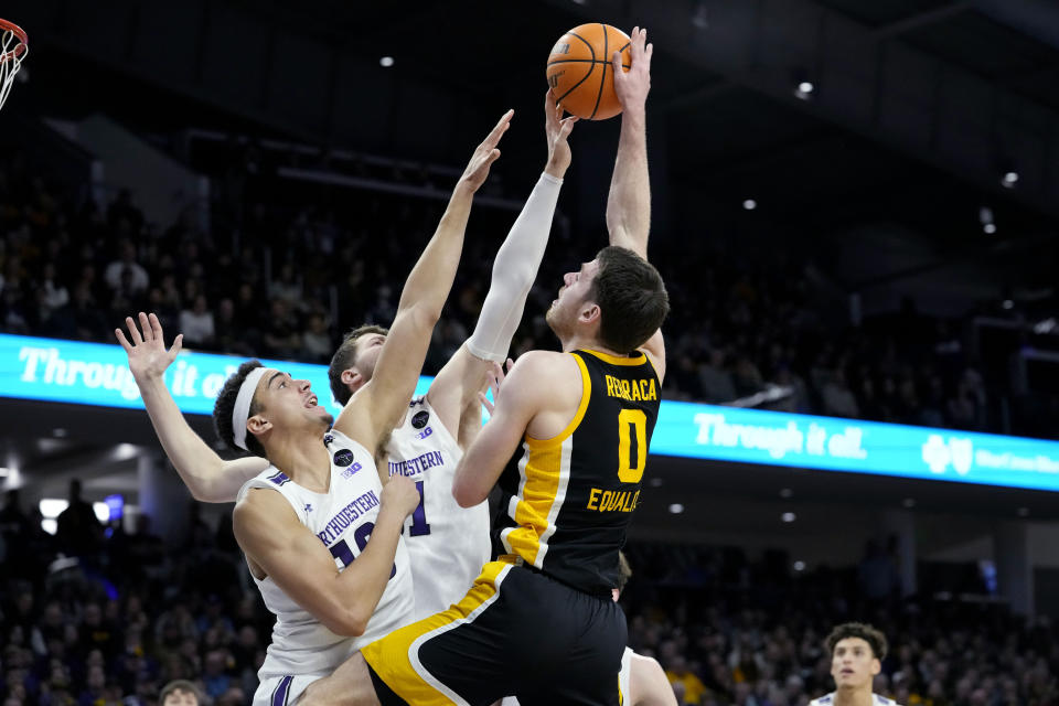 Northwestern forwards Tydus Verhoeven, left, and Robbie Beran, center, try to block a shoot by Iowa forward Filip Rebraca during the first half of an NCAA college basketball game in Evanston, Ill., Sunday, Feb. 19, 2023. (AP Photo/Nam Y. Huh)