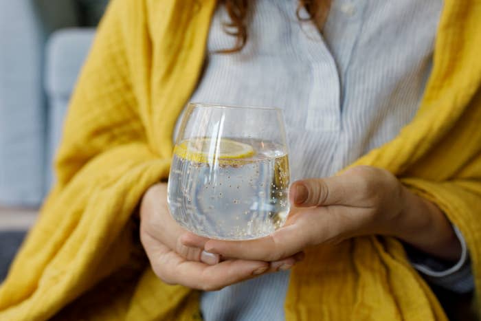 A woman holding a glass of sparkling water with lemon