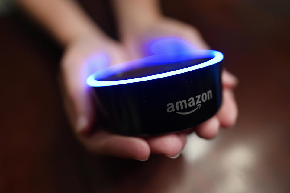 FILE - In this Aug. 16, 2018, file photo a child holds his Amazon Echo Dot in Kennesaw, Ga. From what you buy online, to how you remember tasks, to when you monitor your doorstep, Amazon is seemingly everywhere. And it appears the company doesn’t want to halt its reach anytime soon. In recent weeks, Amazon has said it will spend billions of dollars in two gigantic acquisitions that, if approved, will broaden its ever growing presence in the lives of consumers. (AP Photo/Mike Stewart, File)