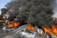 Smoke rises from burning tires ignited by Iraqi demonstrators to block a road during ongoing anti-government protests in Najaf