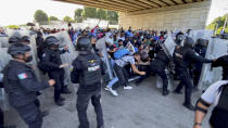 A caravan of migrants, most from Central America, break through a Mexican police barricade in Tapachula, Mexico, Saturday, Oct. 23, 2021. Immigration activists say they will lead migrants out of the southern Mexico city of Tapachula Saturday at the start of a march they hope will bring them to Mexico City to press their case for better treatment. (AP Photo/ Edgar H. Clemente)