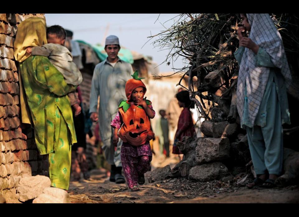 Una niña paquistaní viste un disfraz de calabaza mientras camina por un barrio pobre en Islamabad.