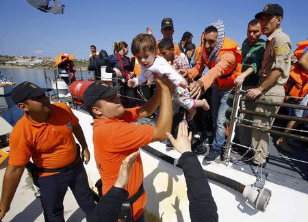 Members of the Turkish coast guards hold a baby of a Syrian migrant on the shore in Cesme, near the Aegean port city of Izmir, Turkey, August 11, 2015. REUTERS/Osman Orsal
