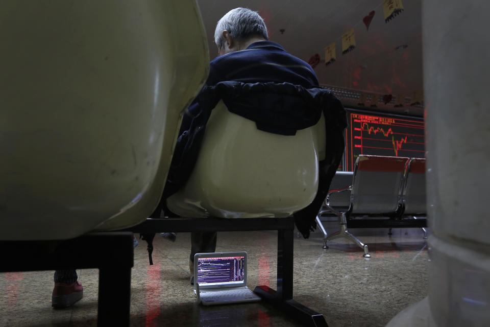 An investor places his computer showing shares index under his seat as he takes a nap at a brokerage house in Beijing, Tuesday, Jan. 22, 2019. Asian markets were mostly lower on Tuesday after the International Monetary Fund trimmed its global outlook for 2019 and 2020. This came after China said its economy grew at the slowest pace in 30 years. (AP Photo/Andy Wong)