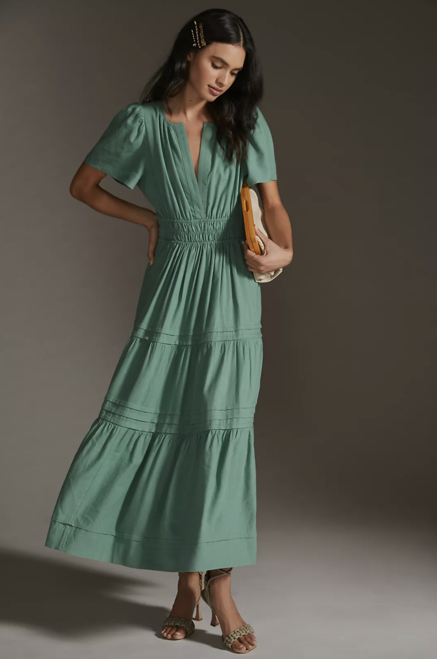 model with curly black hair in sandals and Anthropologie Somerset Linen Maxi Dress in Green (Photo via Anthropologie)