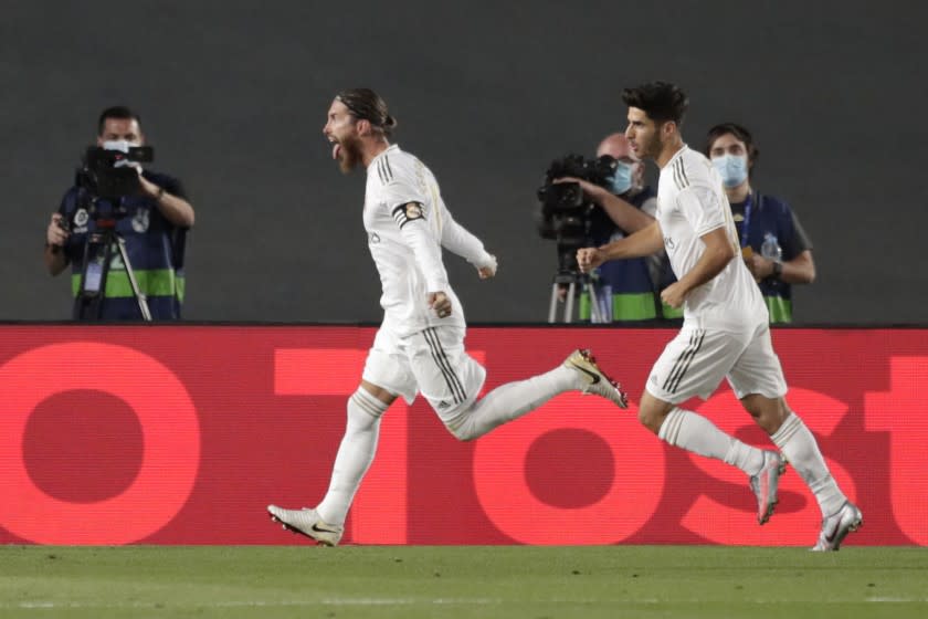 Real Madrid's Sergio Ramos, left, celebrates after scoring his side's opening goal from a penalty shot during the Spanish La Liga soccer match between Real Madrid and Getafe at the Alfredo di Stefano stadium in Madrid, Spain, Thursday, July 2, 2020. (AP Photo/Bernat Armangue)