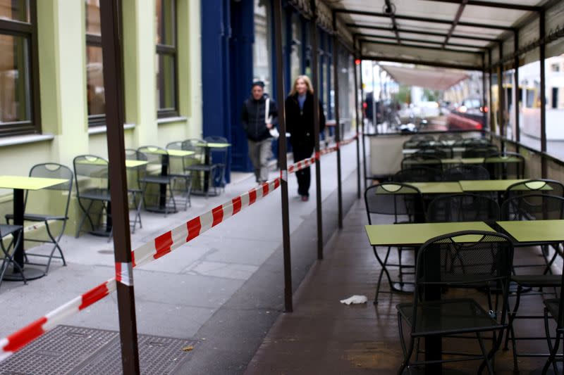 People walk next to abandoned tables of a restaurant during the second lockdown as the coronavirus disease (COVID-19) outbreak continues in Vienna