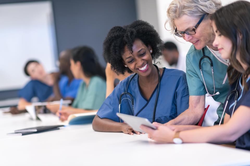 This stock photo shows a group of nurses working together in a classroom setting.