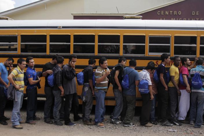 Deportees line up outside a bus at the Care Center for Returning Migrants (CAMR) after arriving on an immigration flight from the U.S., at the international airport in San Pedro Sula November 20, 2013. According to the General Directorate of Migration and Immigration, 32,240 Hondurans were deported by air from the U.S. in 2012. Honduras is heading for a close presidential vote on Sunday as the wife of an ousted leftist leader fends off a late surge from the ruling party heavyweight and both vow a crackdown on drug violence that has made the country the world's murder capital. The winner of Sunday's election will have to steady state finances, clean up a corrupt police force and fight drug gangs that have given the impoverished country the highest homicide rate in the world of more than 85 people per 100,000. Picture taken November 20, 2013. REUTERS/Jorge Cabrera (HONDURAS - Tags: CRIME LAW CIVIL UNREST POLITICS ELECTIONS)