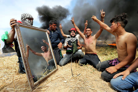 Palestinian activists are seen reflected in a mirror as they gather at the Israel-Gaza border, in the southern Gaza Strip April 2, 2018. REUTERS/Ibraheem Abu Mustafa