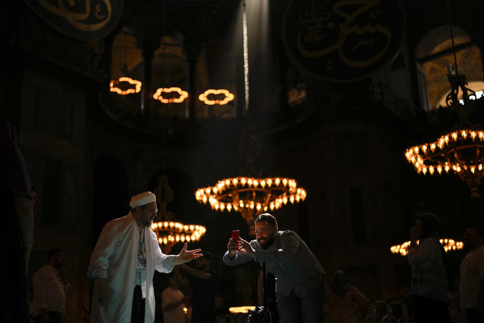 Un trabajador le pide a un guía turístico que deje de tomar fotos a sus clientes debido al inicio de las oraciones en la mezquita de la era bizantina de Santa Sofía, en Estambul, Turquía, el 28 de junio de 2023. Los lugares sagrados más emblemáticos de Europa luchan este verano con un turismo que ya alcanzó o incluso superó los niveles previos a la pandemia. Tratan de hallar formas de acomodar tanto a los fieles que vienen regularmente a orar como a los millones de visitantes atraídos por el arte y la arquitectura. (AP Foto/Francisco Seco)