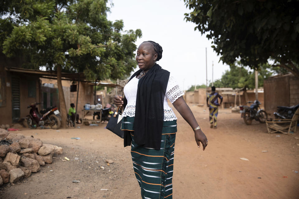 Mariama Sawadogo, 44, walks to her work as a radio host at Zama Radio, in Kaya, Burkina Faso, Monday, Oct. 25, 2021. Many guests and listeners in Burkina Faso call her "aunty" as she gently guides them to the right answers and awards prizes such as soap and washing buckets. In the West African country of Burkina Faso, many feel the government has let them down during the pandemic. Tests, vaccines and messaging often miss many residents, despite a $200 million budget for virus-response efforts. In a region where women are responsible for family work and community relationships, they’ve stepped up to fill in gaps. (AP Photo/Sophie Garcia)