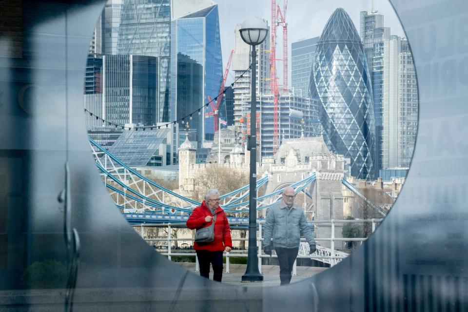 pensioners Two elderly people walk past a circular portal in front of the City of London, the capital's financial district, on 23rd February 2022, in London, England.