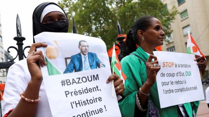Demonstrators hold placards and Niger flags as they gather outside the country's embassy in Paris in support of President Mohamed Bazoum
