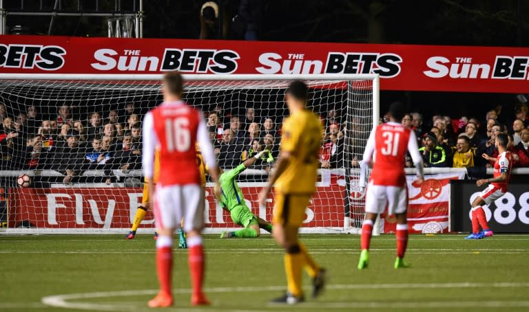 Arsenal's English midfielder Theo Walcott (R) watches his shot as he scores their second goal, his 100th goal for Arsenal, during the English FA Cup fifth round football match between Sutton United and Arsenal on February 20, 2017