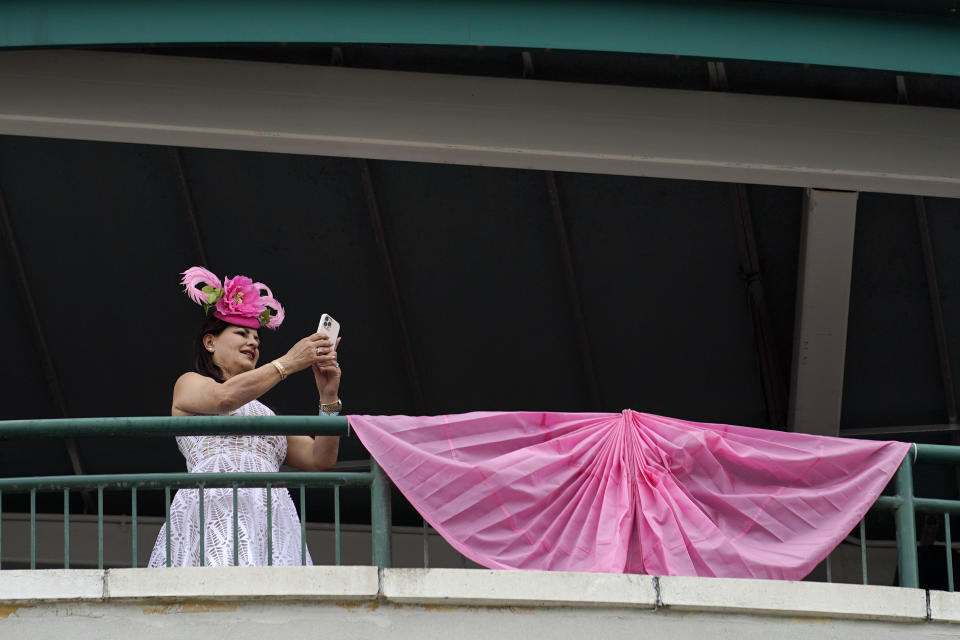A woman makes photos from a balcony at Churchill Downs before the 148th running of the Kentucky Oaks horse race Friday, May 6, 2022, in Louisville, Ky. (AP Photo/Brynn Anderson)