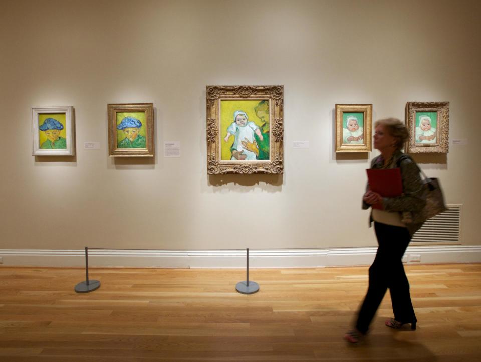 In this Oct. 8, 2013 photo, a woman walks past Vincent van Gogh pieces, including "Portrait of Camille Roulin," left, and "Portrait of Marcelle Roulin," right, on display at The Phillips Collection in Washington. In the midst of the shutdown of federally funded museums, the private Phillips Collection is launching the first major exhibition of Vincent van Gogh’s artwork in Washington in 15 years. (AP Photo/Molly Riley)