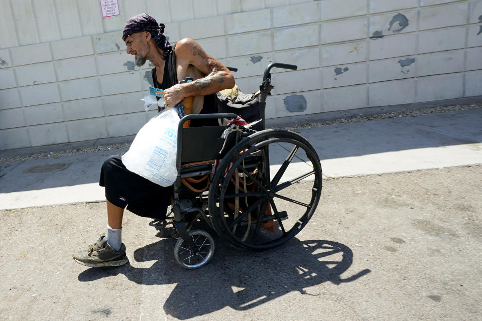 Charles Sanders, 59, brings ice to his tent inside a homeless encampment called "The Zone," Friday, July 14, 2023, in downtown Phoenix. Sanders, from Denver, has been spending the days at the Justa Center, a day center for homeless people 55 years and older in the downtown area. Several dozen people stop by daily for cold water, a meal, a shower and an electrical outlet to charge a mobile phone. (AP Photo/Matt York)