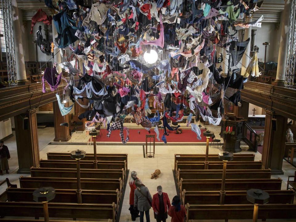 People view an installation artwork called Suspended, composed of items of clothing discarded by refugees on their arrival at Lesvos, by artist Arabella Dorman, at St James's Church on Piccadilly in London (AP)