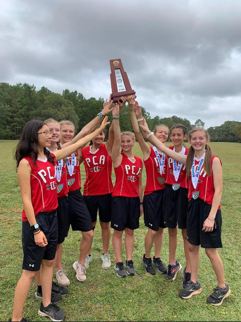 The Pensacola Christian Academy girls cross country team holds up its first-ever regional championship trophy after capturing the Region 1-1A title on Friday, Oct. 28, 2022 from the New World Golf Complex in Jacksonville.
