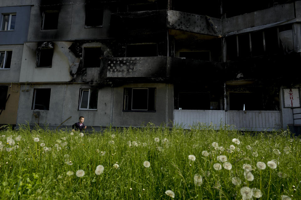 A boy runs in front of a building destroyed by attacks in Borodyanka, on the outskirts of Kyiv, Ukraine, Tuesday, May 31, 2022. (AP Photo/Natacha Pisarenko)