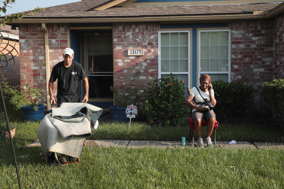 Lillie Roberts talks with family members on the phone as contractor Jerry Garza begins the process of repairing her home.