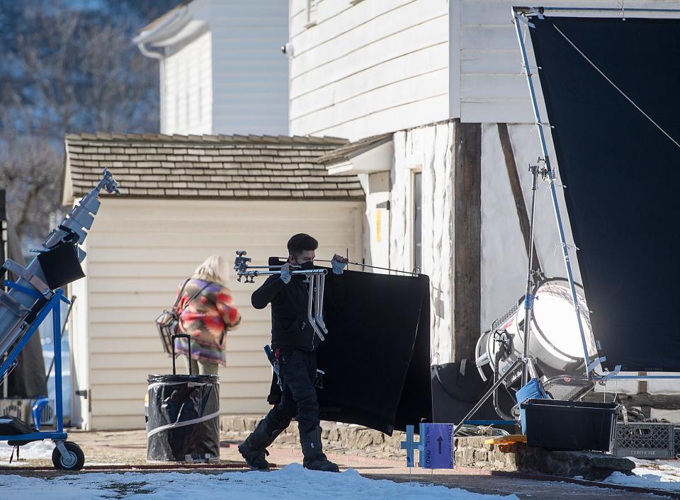 A crew member carries equipment at Old Economy Village where filming for the Netflix movie "The Pale Blue Eye" took place Friday in Ambridge.