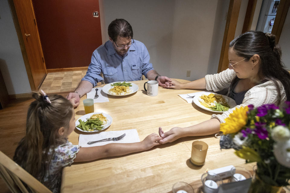 Shane Alderson, his wife, Alisha, and their daughter, Adeline, 5, pray before dinner at their home in Baker City, Ore., on Thursday, Aug. 31, 2023. Shane is Baker County's chief commission chair and Alisha is expecting their daughter, Ava, in September. Because of the closing of Baker City's only obstetrical unit, the family is traveling to the Boise, Idaho area, a little over 100 miles away, to give birth. (AP Photo/Kyle Green)