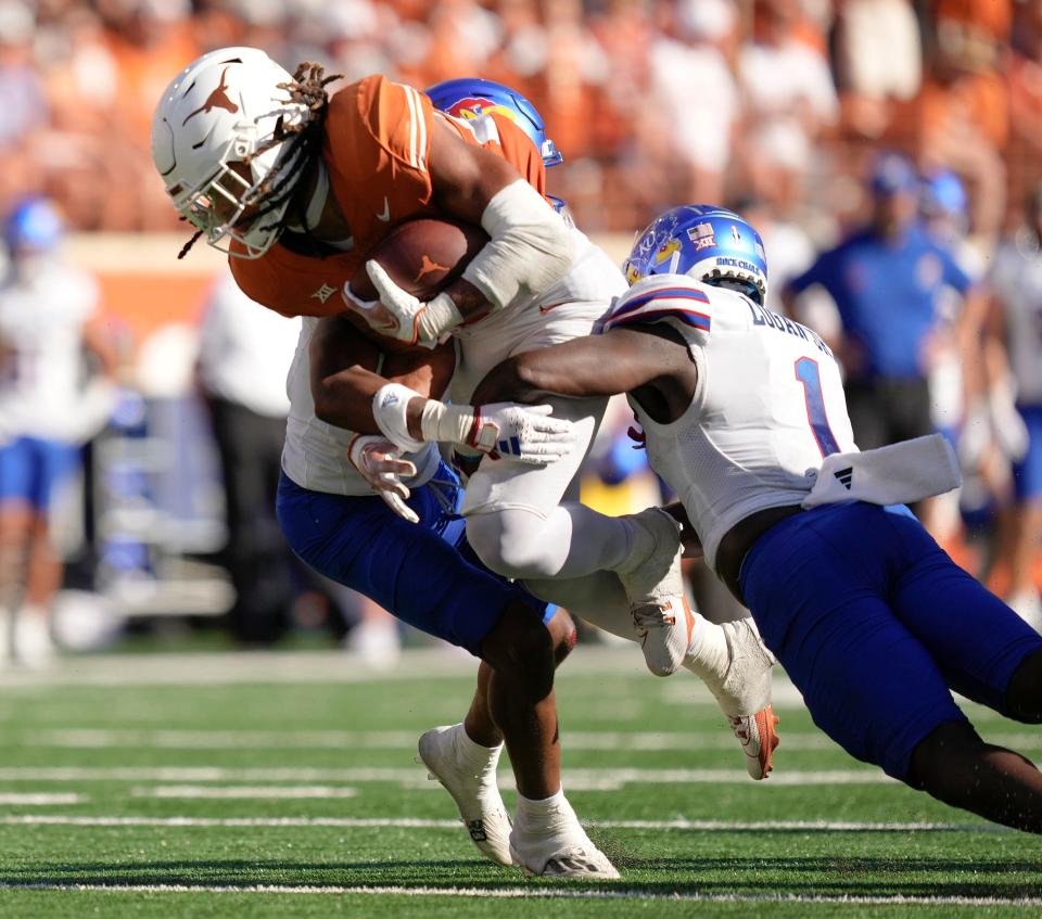 Texas Longhorns running back Jonathon Brooks is tackled by Kansas Jayhawks safety O.J. Burroughs and safety Kenny Logan Jr. in the third quarter at Royal-Memorial Stadium on Saturday September 30, 2023.