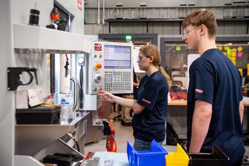 Oak Ridge High students Lauren Gross, left, and Blayne Quilty watch as a piece is made in a 5-axis CNC machine in Oak Ridge High's machine shop on Friday, June 16, 2023. Oak Ridge High students are gaining practical, hands-on manufacturing training through the America's Cutting Edge program.