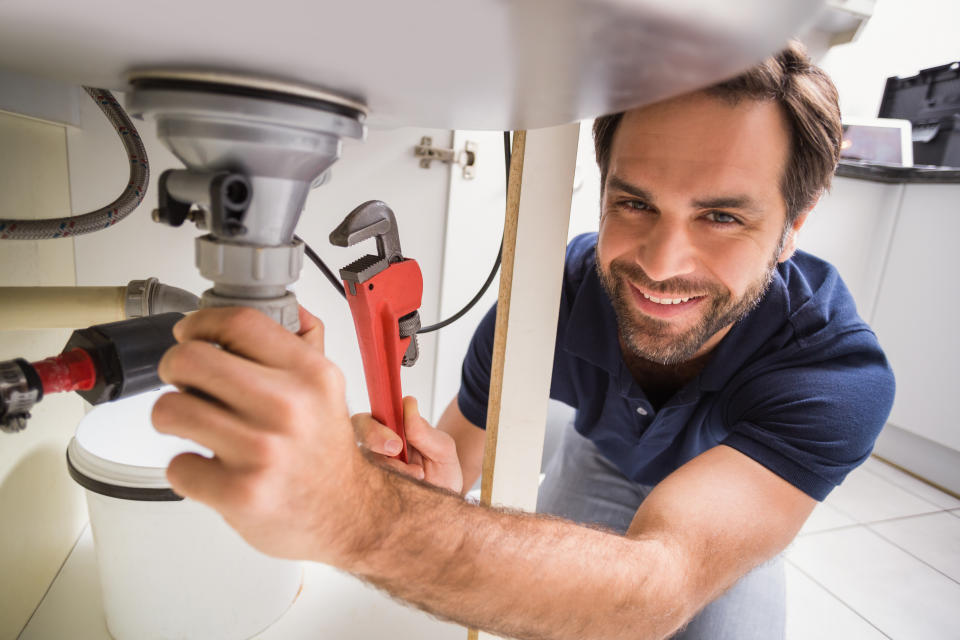 Plumber fixing under the sink in the kitchen