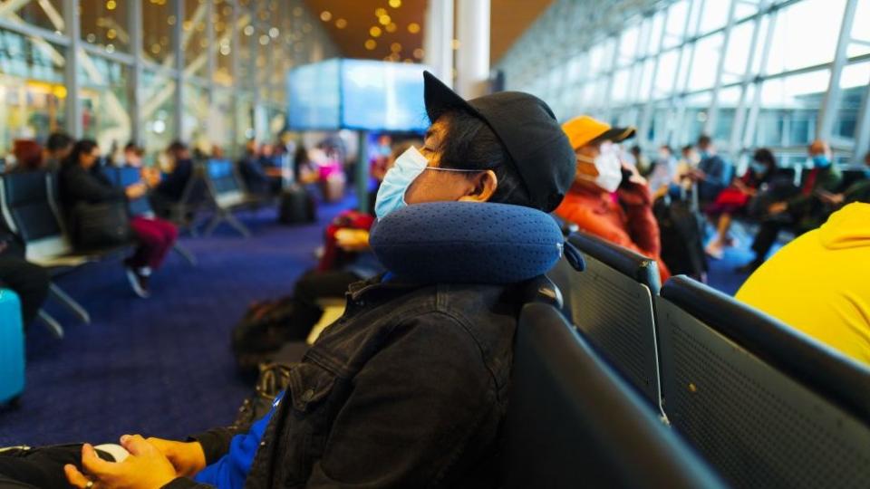 Ciudadanos esperando vuelo en aeropuerto.