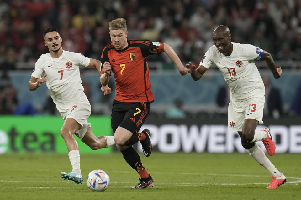 Canada's Atiba Hutchinson, right, and Canada's Stephen Eustaquio, left, challenge for the ball with Belgium's Kevin De Bruyne, centre, during the World Cup group F soccer match between Belgium and Canada, at the Ahmad Bin Ali Stadium in Doha, Qatar, Wednesday, Nov. 23, 2022. (AP Photo/Hassan Ammar)