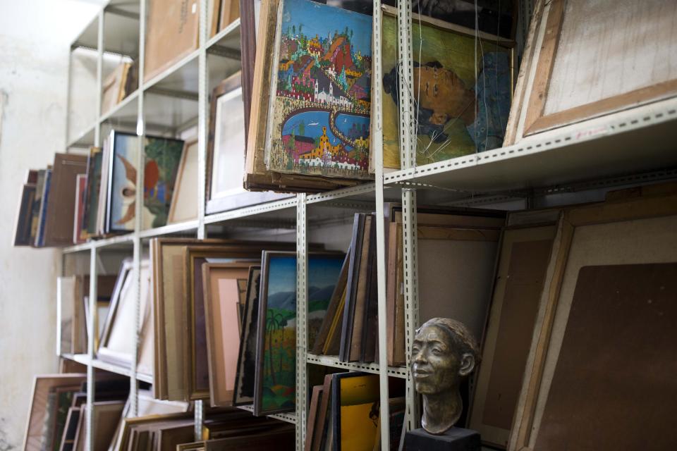 In this July 4, 2019 photo, paintings sit in storage at the Musée d'Art du Collège Saint Pierre, in Port-au-Prince, Haiti. Today the museum is still a collection of blank, white walls, with hundreds of paintings stacked in a narrow storage area exposed to heat, humidity and other dangers. They are taken out only for the occasional cleaning. (AP Photo/Dieu Nalio Chery)