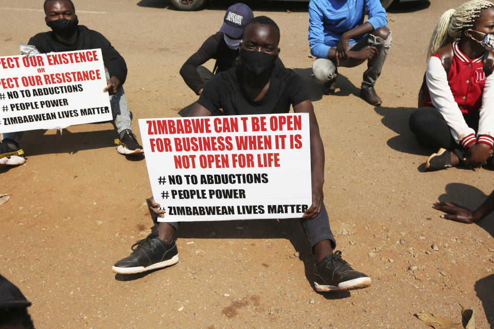 FILE - In this Monday, Sept. 14, 2020 file photo, a student and human rights activist holds a banner with others during a peaceful protest in Harare, Zimbabwe. Human rights defenders say it appears the government is using restrictions imposed to combat COVID-19 to suppress political criticism. Opposition officials, human rights groups and some analysts accuse President Emmerson Mnangagwa of abusing the rights of critics, using tactics as harsh as his predecessor, the late Robert Mugabe. (AP Photo/Tsvangirayi Mukwazhi, File)